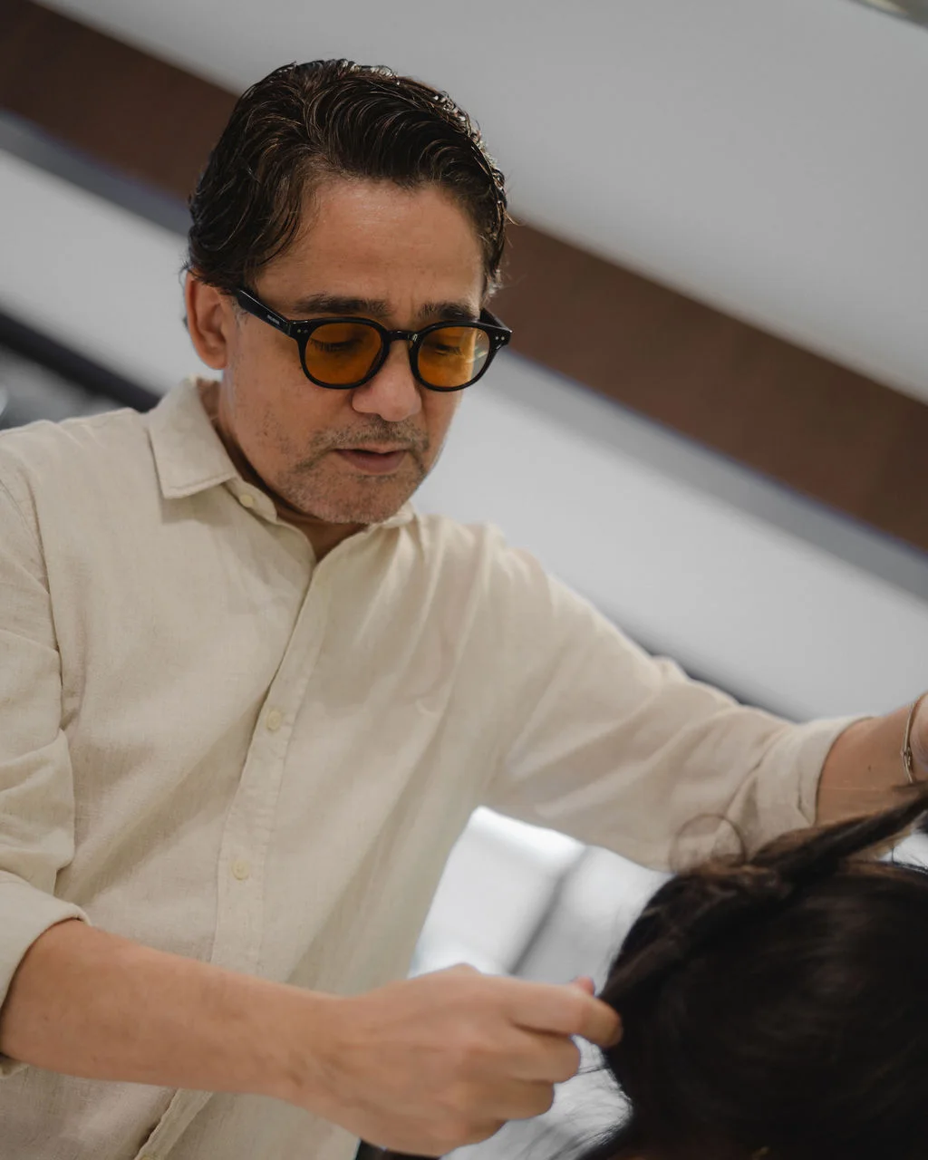 Kleber Rodrigues trabalhando no cabelo de uma cliente, em preto e branco