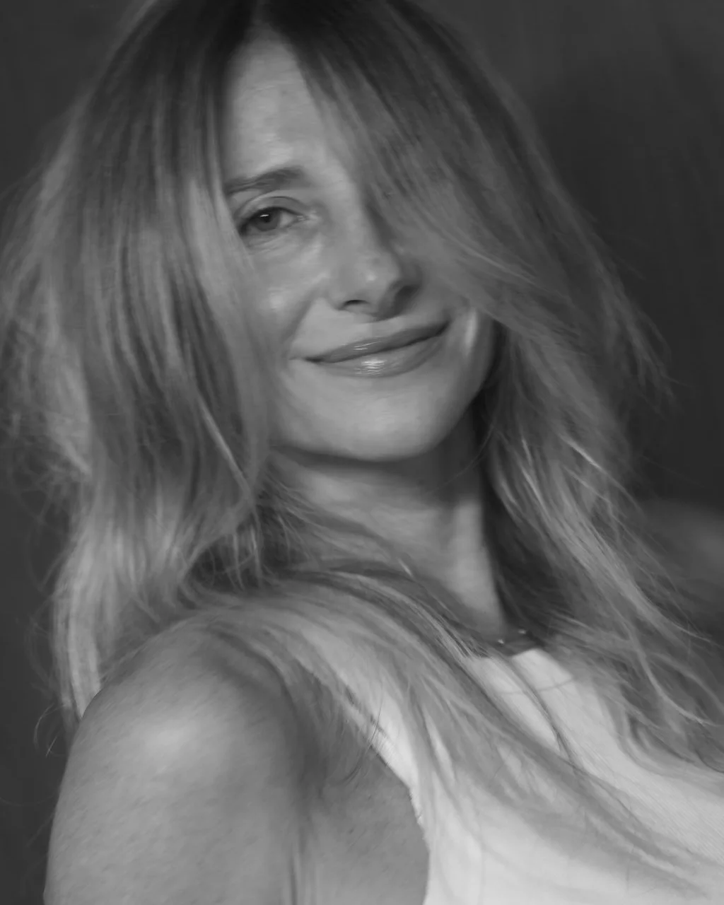 Retrato em preto e branco de mulher sorrindo, cabelo loiro longo em movimento